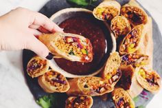 a hand holding a burrito over a plate full of food