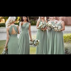 a group of women standing next to each other holding bouquets and wearing green dresses