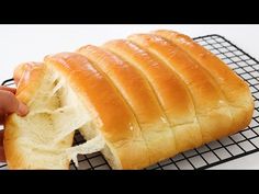 a person holding a loaf of bread on top of a cooling rack with it's end cut off