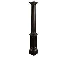 a tall black clock tower sitting on top of a white floor next to a lamp post