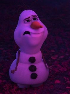 a purple snowman sitting on top of leaves in the night time with its eyes closed