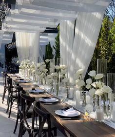 a long table with white flowers in vases on it