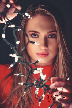 a beautiful young woman with long blonde hair and blue eyes is surrounded by christmas lights