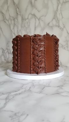 a chocolate cake sitting on top of a white plate next to a marble countertop