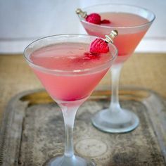 two martinis with raspberries sit on a tray