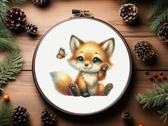 a cross stitch pattern with a little fox on it's side and pine cones in the background