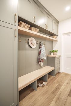 a wooden bench sitting next to a wall filled with cabinets and baskets on top of it