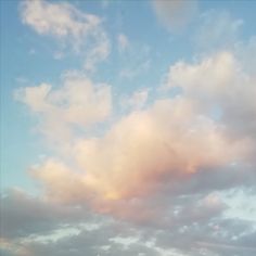 the airplane is flying high in the sky with some clouds behind it and another plane on the ground