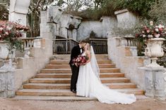 a bride and groom standing in front of some stairs