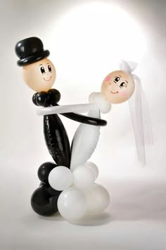 a couple holding hands with balloons in the shape of two people on top of each other