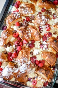 croissants covered in powdered sugar and raspberries on a baking sheet