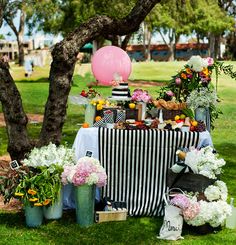 a table topped with lots of food next to a pink balloon in the air and flowers