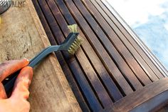 a person using a brush to clean a wooden bench