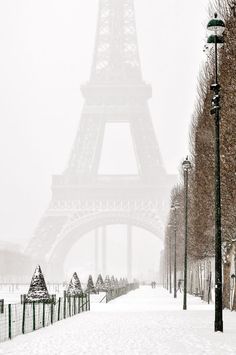 the eiffel tower is covered in snow as people walk by on a snowy day