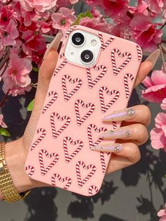 a woman holding up a pink phone case with candy canes on the front and sides