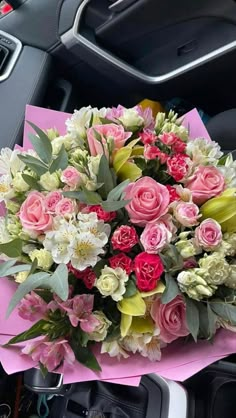 a bouquet of flowers sitting on top of a pink paper next to a steering wheel