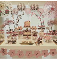 a table topped with lots of cakes and desserts next to an umbrella covered wall