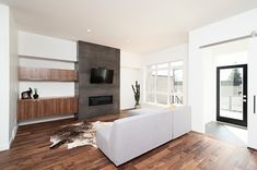 a modern living room with wood flooring and white furniture