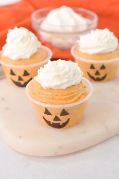 three pumpkin cupcakes with whipped cream on top