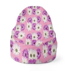 a pink beanie hat with white and purple daisies on the front, sitting in front of a white background