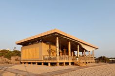 a wooden structure sitting on top of a sandy beach next to the ocean with steps leading up to it