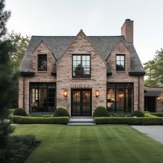 a large brick house with lots of windows and bushes in front of the entrance to it