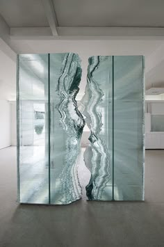 an abstract glass sculpture in the middle of a room with white walls and flooring