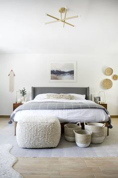 a bedroom with white walls and flooring, including a large bed surrounded by baskets