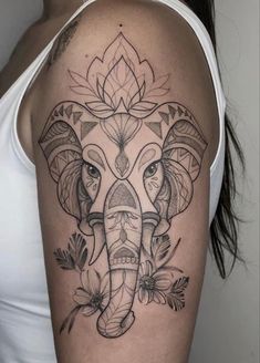 an elephant tattoo on the right arm and shoulder, with flowers around its head in black ink