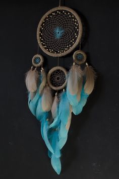 a blue and white dream catcher hanging from a hook on a black wall with feathers