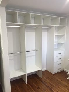 an empty white closet with wooden floors and shelves