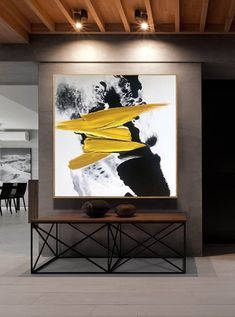 an abstract painting hangs on the wall above a console table in a modern living room