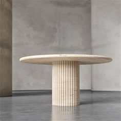 a round table with columns on it in front of a gray wall and concrete floor