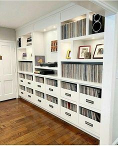 a room filled with lots of white bookshelves covered in vinyl records and cd's