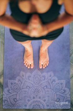 a woman standing on a yoga mat with her feet up