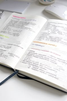 an open book with writing on it sitting next to a computer mouse and other office supplies