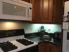 a stove top oven sitting inside of a kitchen next to a microwave and toaster oven