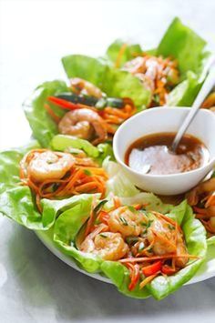 a plate filled with lettuce and shrimp next to dipping sauce on the side