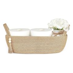 two rolls of toilet paper in a woven basket with white flowers on the side and a tasseled handle