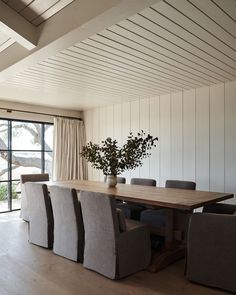 a dining room table with six chairs and a vase on top of it in front of a sliding glass door