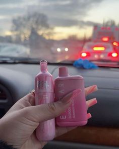 a woman holding two baby bottles in her hand while sitting in the backseat of a car