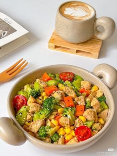 a bowl filled with vegetables next to a cup of coffee