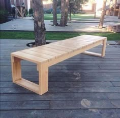 a wooden bench sitting on top of a wooden deck next to a tree and grass