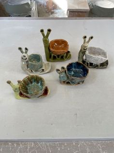 several small ceramic animals sitting on top of a white countertop next to cups and saucers