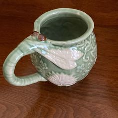 a green and white ceramic coffee mug on a wooden table