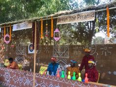 some people are sitting at a food stand with decorations on the wall and trees in the background