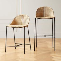 two wicker bar stools sitting next to each other on a hard wood floor