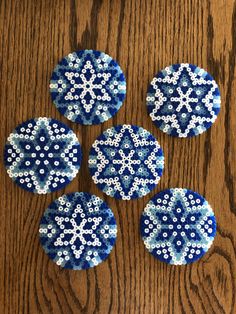 four blue and white snowflakes on a wooden surface