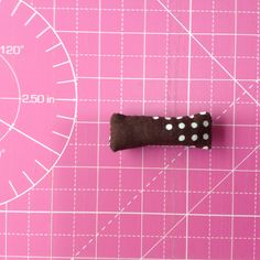 a piece of fabric with white polka dots on it sitting on a pink cutting mat