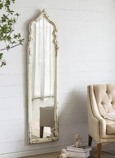 a chair and mirror in a room with white walls